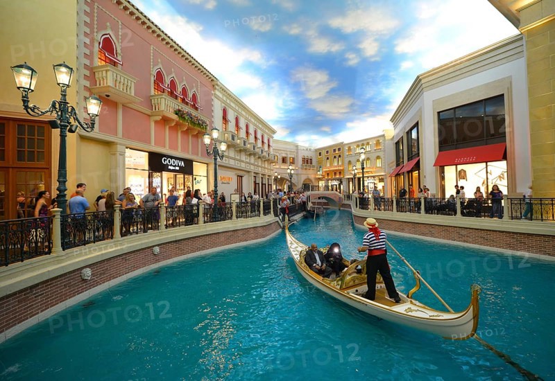 Gondolier in a Gondola with tourists in a replica of Venetian streets under an artificial sky