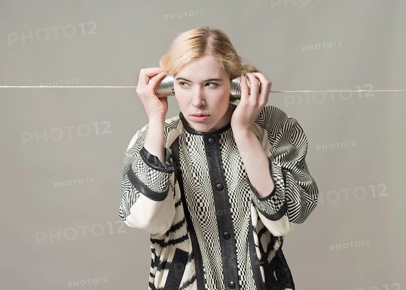 Blond woman listening with tin can phone