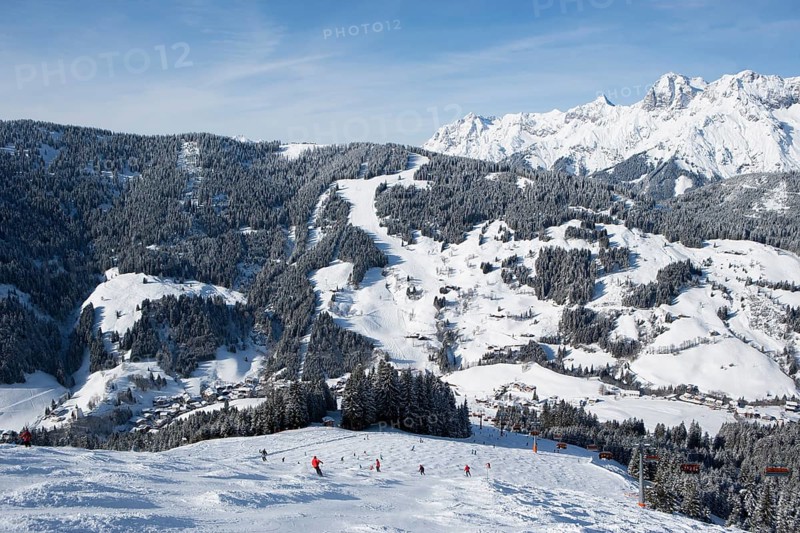 Skiers on slope in front of mountains