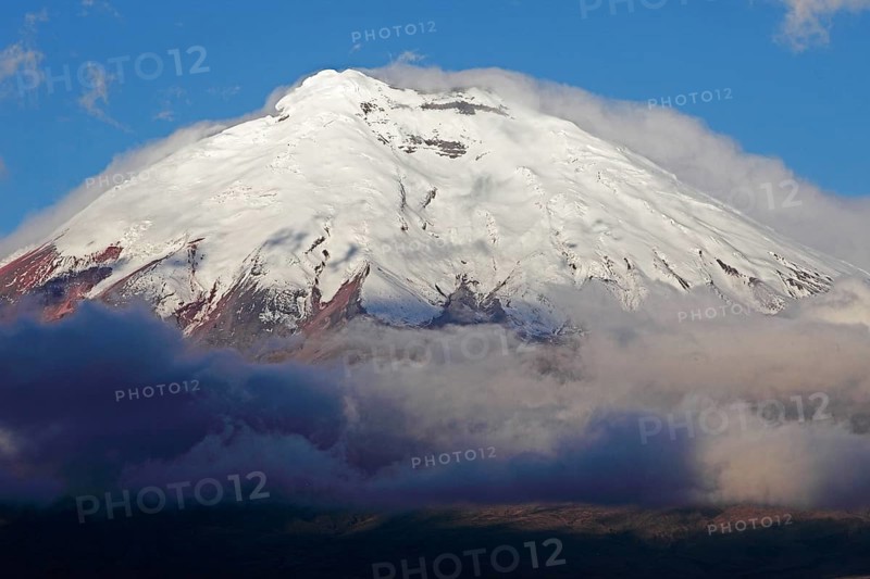 Snow-covered summit of Cotopaxi volcano rising from a cloud cover