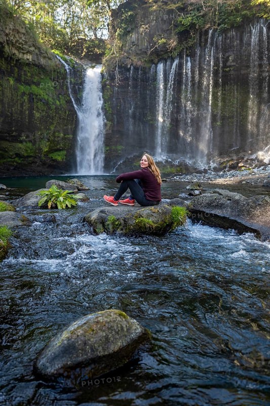 Young woman sitting on a stone in a river