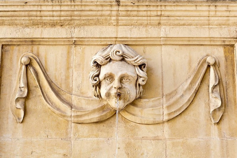 Baroque-style face on a fountain at St. John's Co-Cathedral