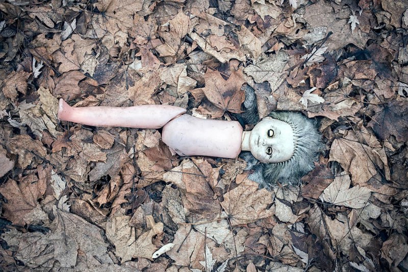 Broken doll lying in the front garden of an abandoned kindergarten