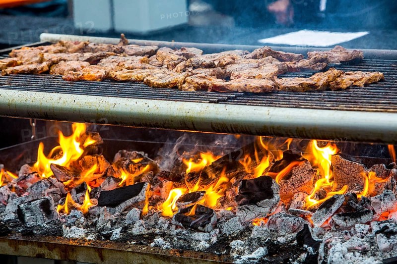 Steaks on a charcoal grill with flames