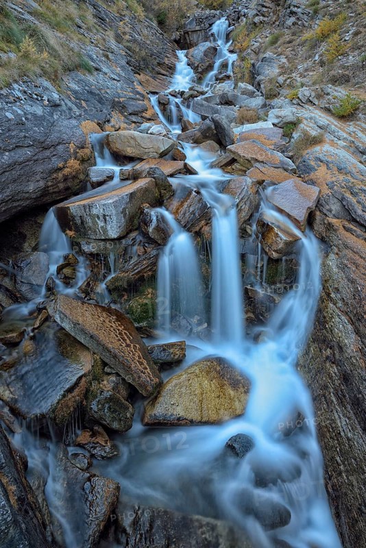 Mountain stream with fallen larch needles on the stones