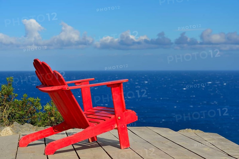 Red wooden chair on a terrace overlooking the Mediterranean Sea