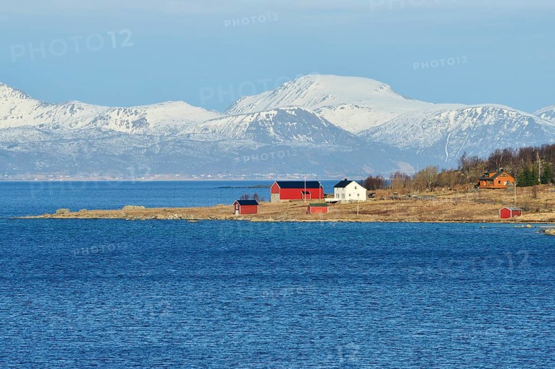 Headland with houses in the blue water of Hadselfjord and Raftsund
