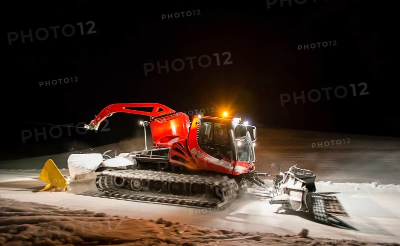 Snowcat planing ski slope with rope at night