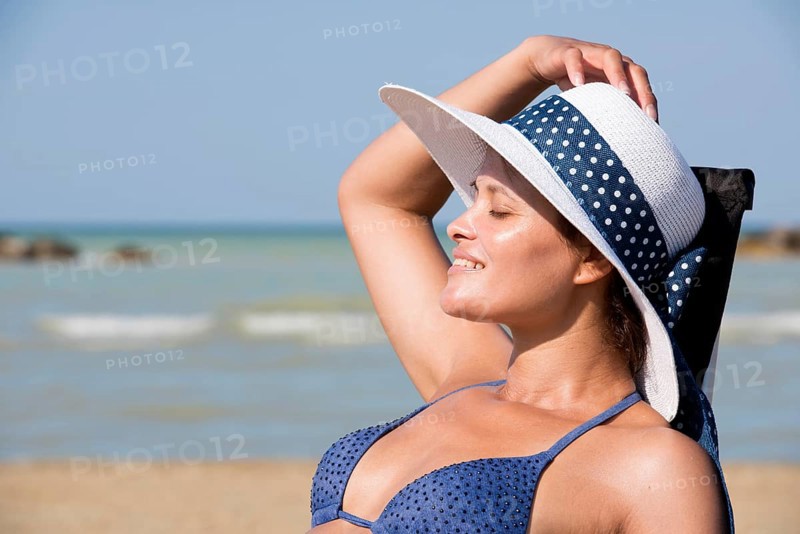 Woman with bikini and sun hat on the beach