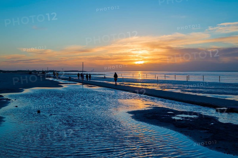 Beach walkers at the Wadden Sea on the North Sea coast in the blue hour at sunset
