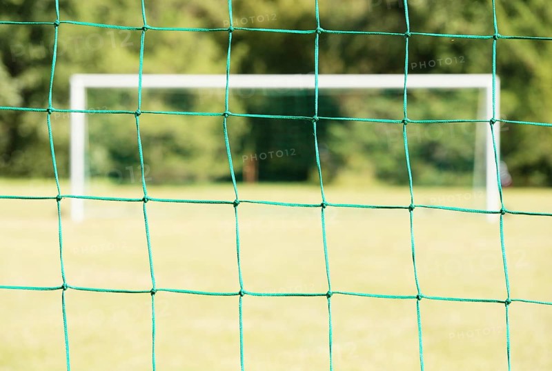 Empty soccer field seen through the net of the goal