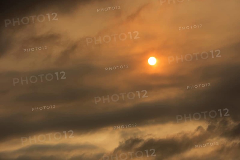 Sun behind clouds and brownish ash and gas clouds of the Holuhraun fissure eruption