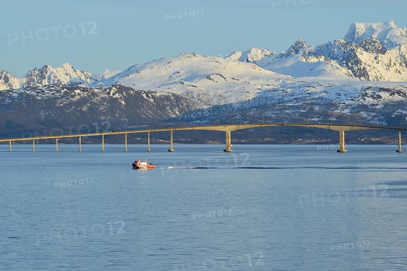 Red boat in front of Hadsel Bridge across the strait