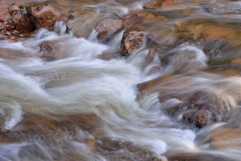 Water running over rocks in a brook in autumn