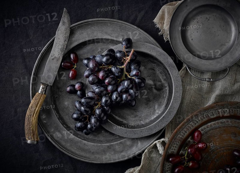 Pewter plates with grapes on a black underground