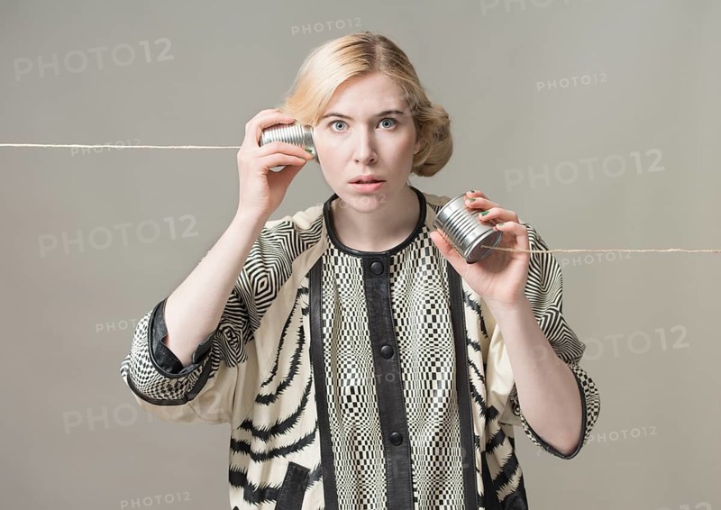 Blond woman listening with tin can phone