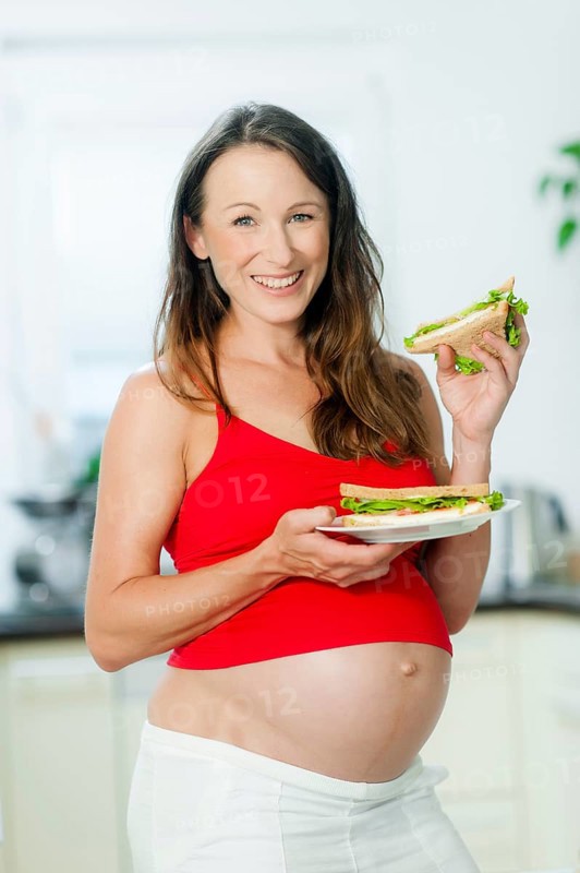 Pregnant woman holding sandwiches