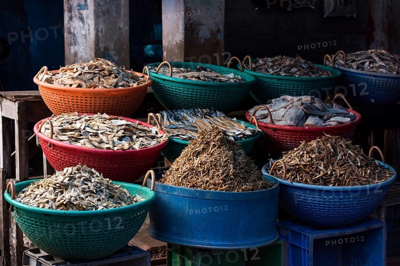 Different types of dried fish in plastic baskets on the market