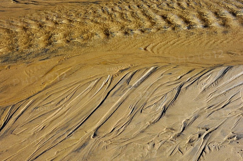 Draining sea water leaving traces in the sand on the beach