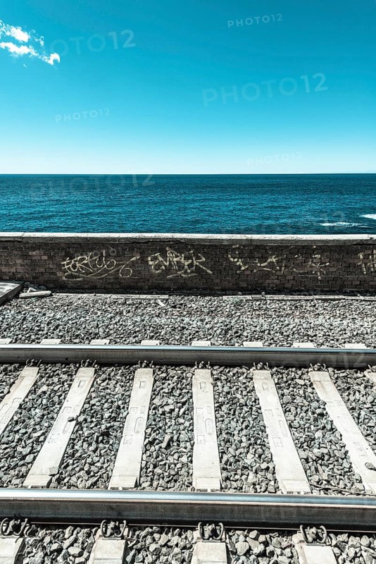 Railroad tracks in front wall with graffiti in front of the sea