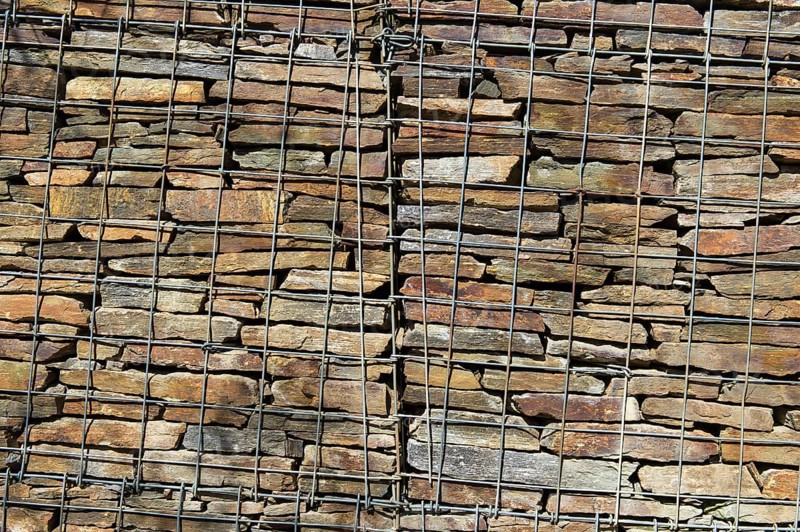 Wall with stacked stones behind steel mesh