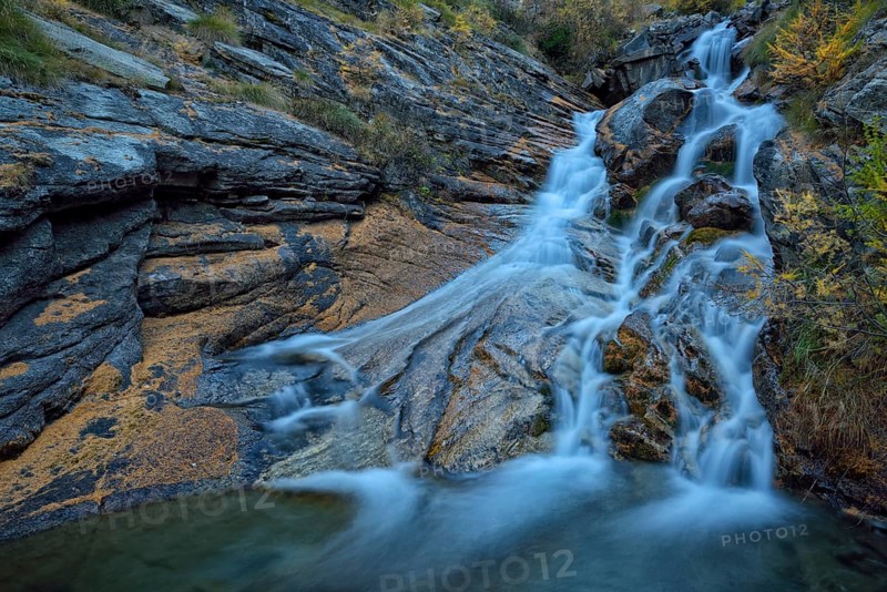 Mountain stream with fallen larch needles on the stones