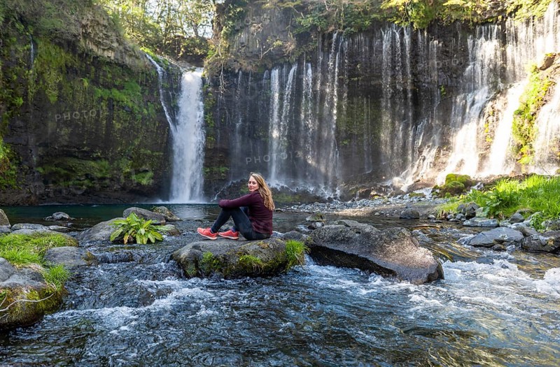 Young woman sitting on a stone in a river