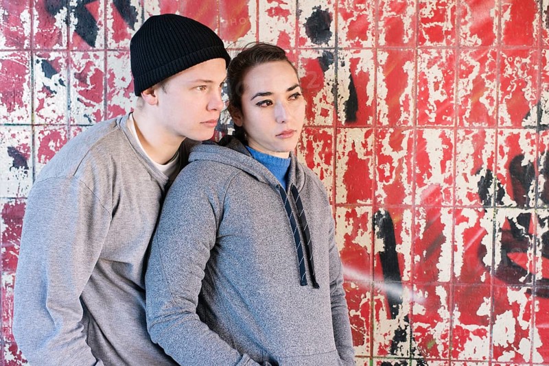 Casual and relaxed young man and woman waiting in front of grafitti wall in urban area