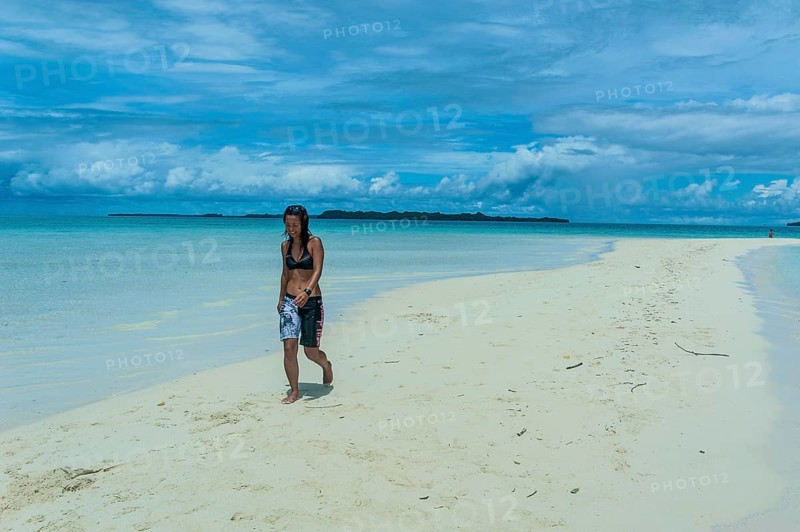 Tourist walking on a sand strip at low tide