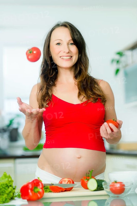 Pregnant woman posing with vegetables