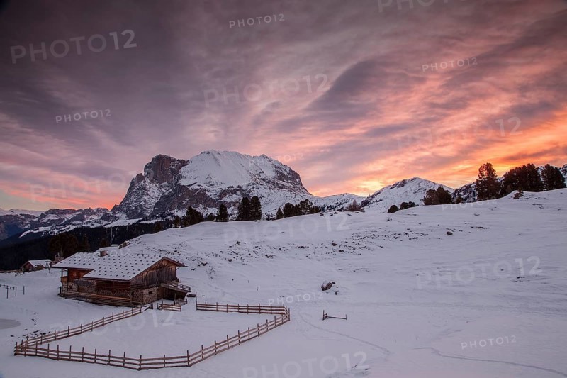 Sunrise over Mt Plattkofel and a mountain hut in winter