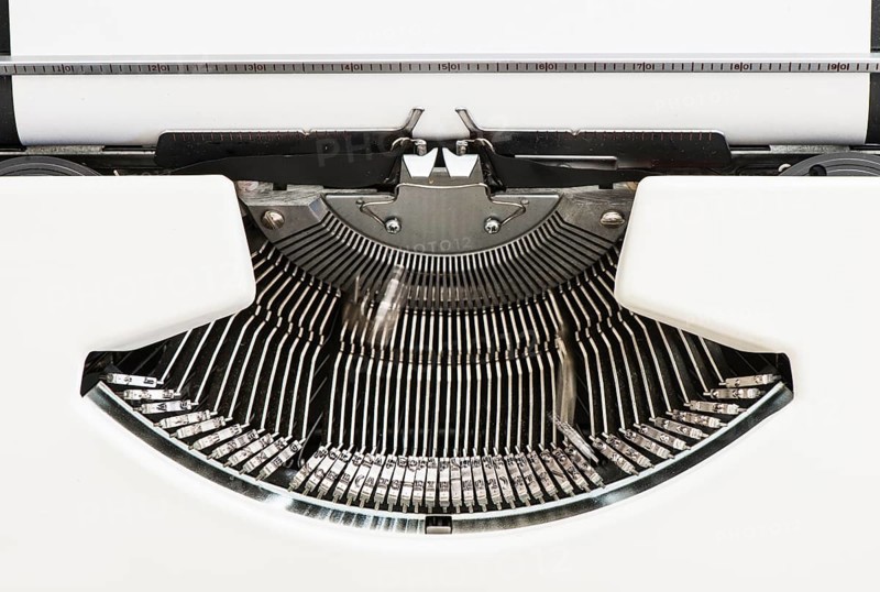 Detail view of an old fashioned typewriter from the 1970s with blank paper and moving hammer heads