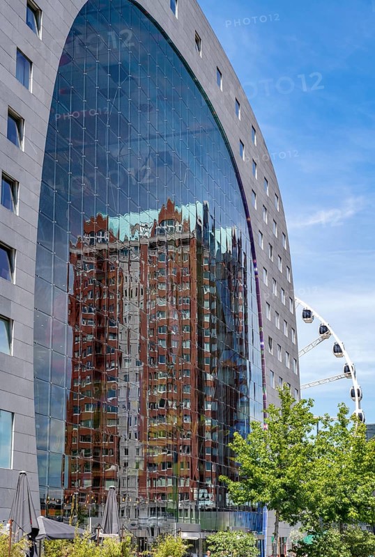 Statendam residential tower reflected in the glass facade of the market hall