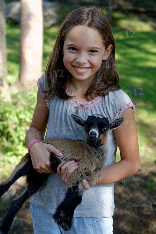 Girl holding a dwarf goat in the petting zoo at Schopperalm