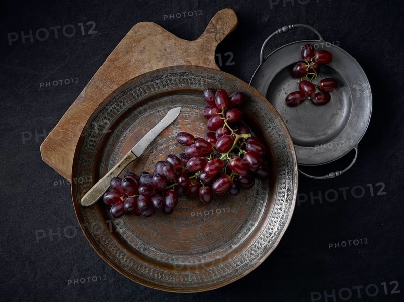 Pewter plates with grapes on a black underground