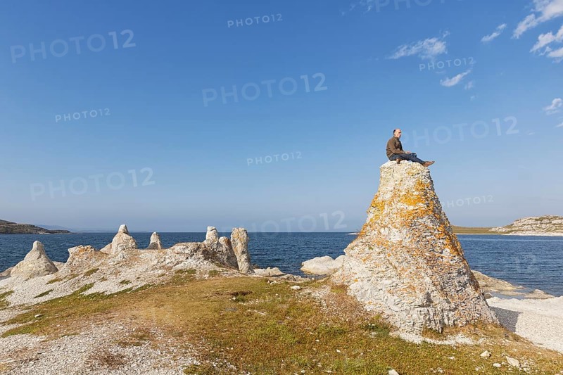 Hiker sitting on one of the legendary dolomite rocks on Porsangerfjorden fjord