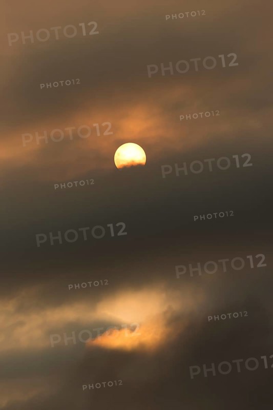 Sun behind clouds and brownish ash and gas clouds of the Holuhraun fissure eruption