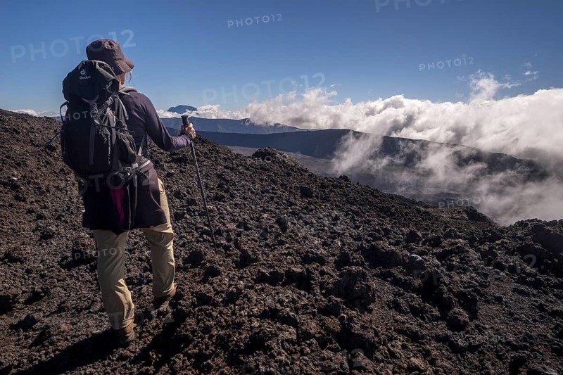 Hiker on the Piton de la Fournaise volcano with views of the Piton des Neiges volcano