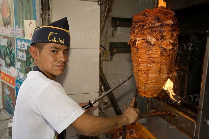 Young man preparing tacos al pastor