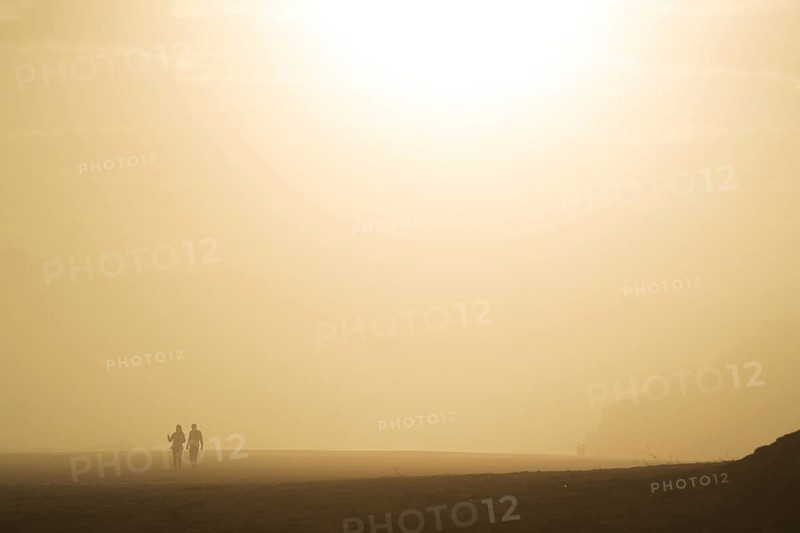 Two people walking at the beach at sunset