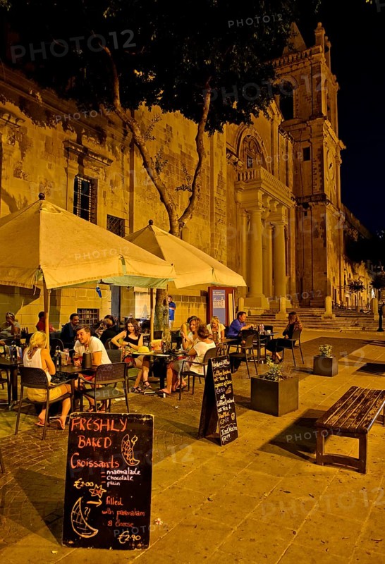 Tourists sitting in an outdoor restaurant at St. John's Co-Cathedral