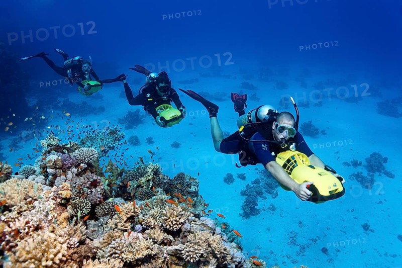 Divers with diver propulsion vehicles exploring a coral reef