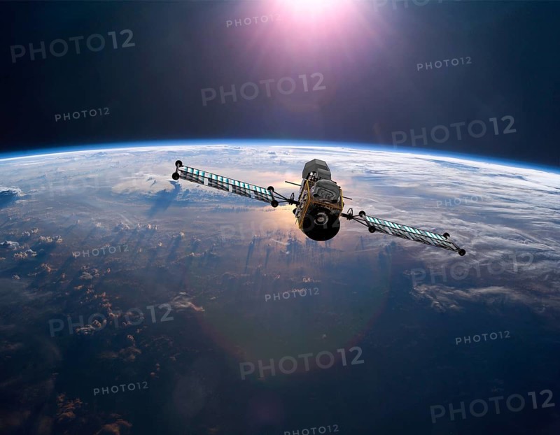 Geostationary orbit military satellite above the Earth pointed toward the rising sun