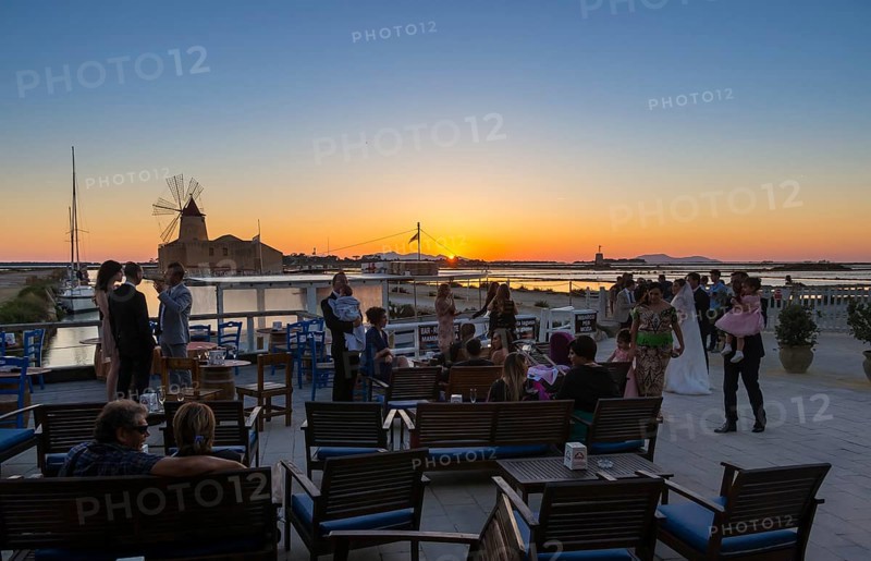 People on the evening in front of the salt pans Ettore Infersa wind mill with salt museum