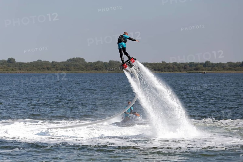 Flyboarder on the water jet of a jet ski