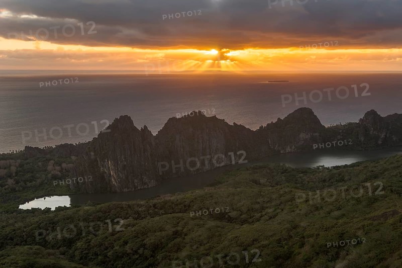 Sun breaking through the clouds over the South Pacific behind the Linderalique Rocks