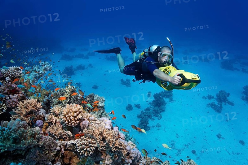Diver with a diver propulsion vehicle exploring a coral reef