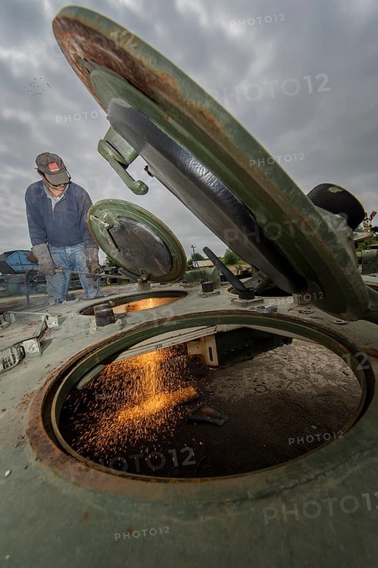 A man cutting up an armored vehicle type Marder with a torch