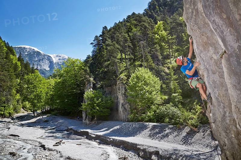 Sport climber wearing a helmet climbing a rock face