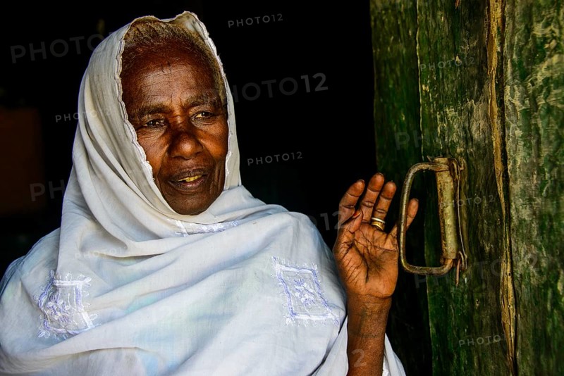 Friendly old woman standing in a door frame near Keren